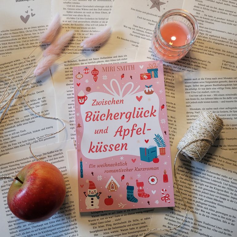 Das Buch Zwischen Bücherglück und Apfelküssen auf losen Buchseiten, neben einem Apfel und goldener Kordel.